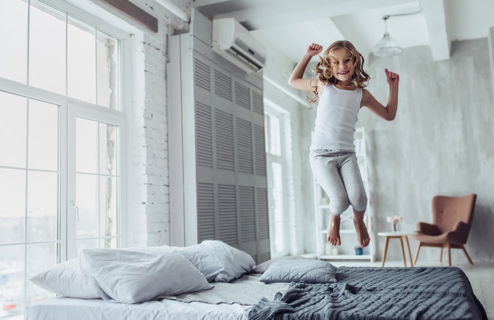 holčička skákající na posteli v dětském pokoji